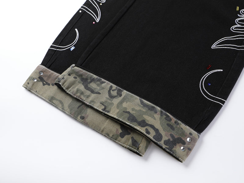 Cuffed hem of black wide-leg jeans with camouflage lining and metal studs