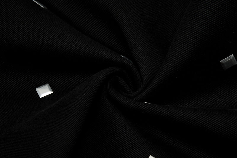 Close-up of black denim fabric with silver square studs