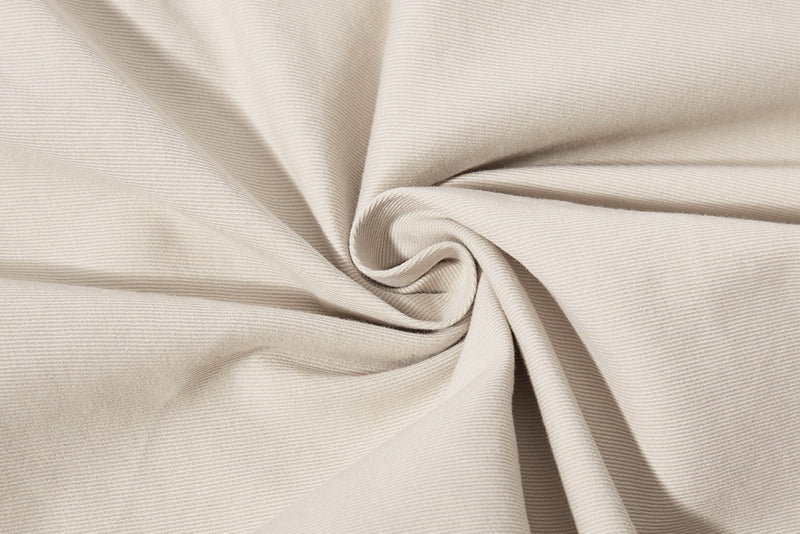Close-up of beige fabric with soft folds and fine twill texture
