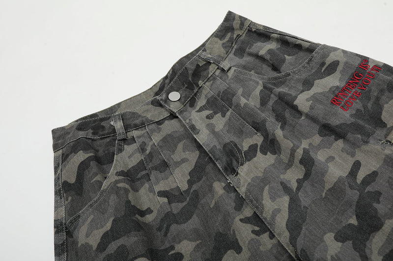 Top front close-up of camouflage shorts showing waistband, button closure, and red embroidery