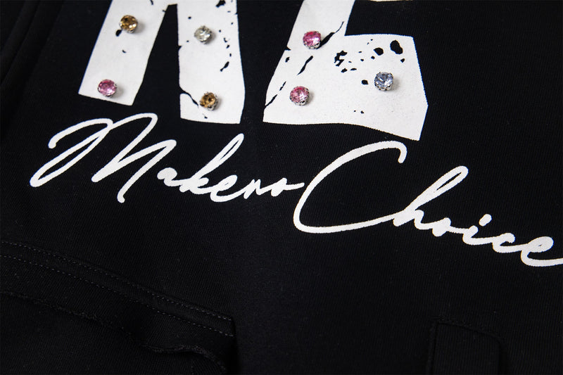 Close-up of black hoodie script text and rhinestone-studded lettering