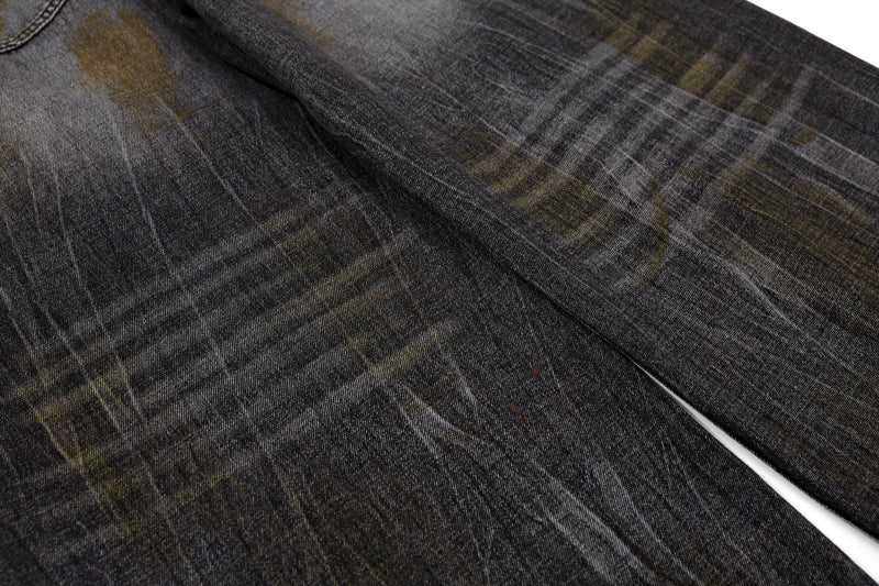 Close-up of black washed denim fabric with faded yellow and brown distressing