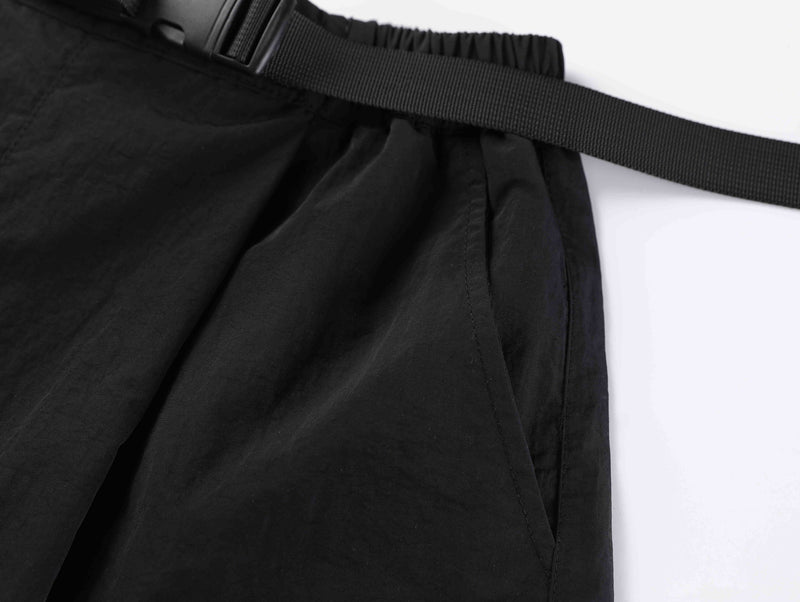Close-up of black shorts belt and gathered waistband from a side angle