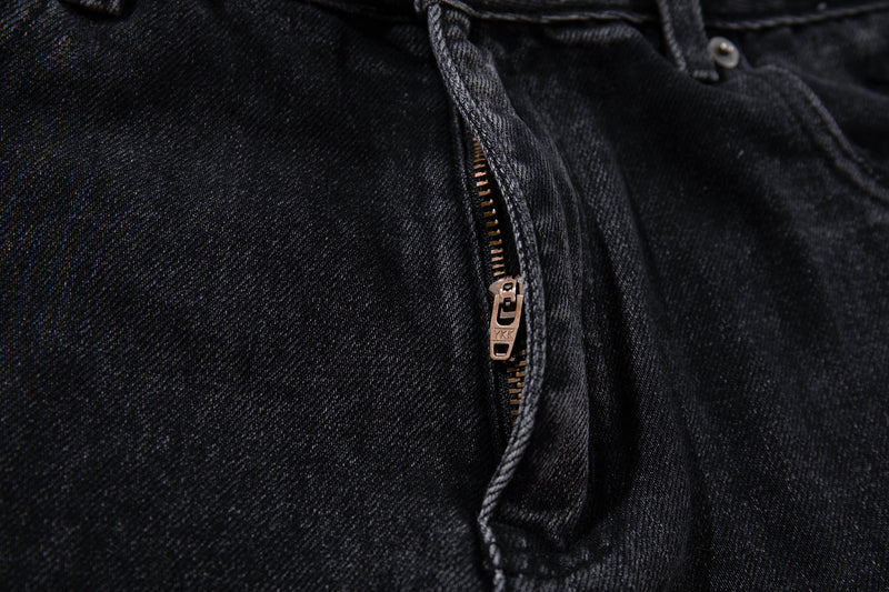 Close-up of jeans fly with bronze zipper and dark charcoal denim texture