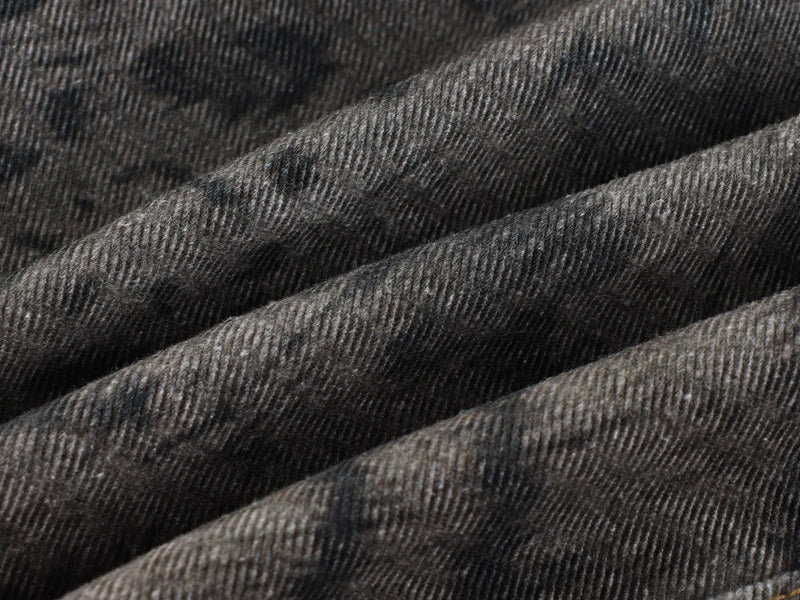 Close-up of dark denim fabric texture with faded mottled pattern