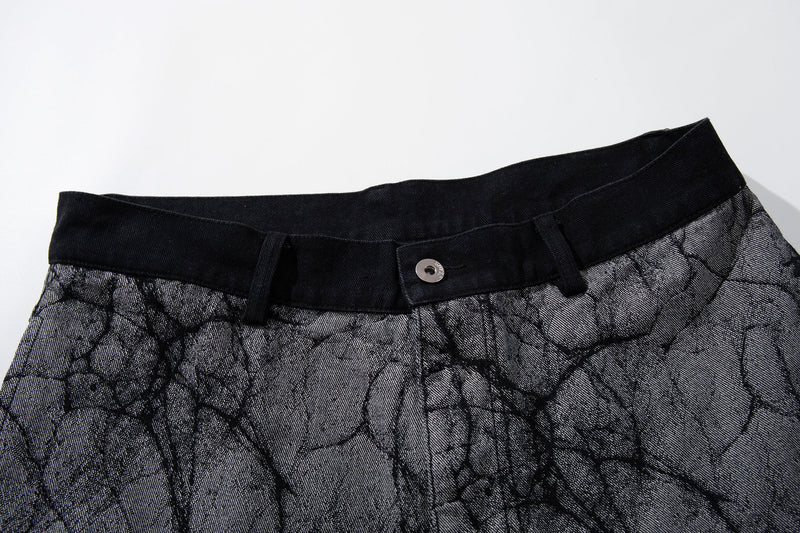 Close-up of black waistband and button on gray cracked-texture denim pants