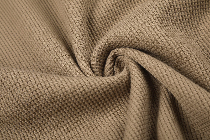 Close-up of tan waffle knit fabric texture draped in folds