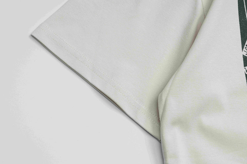 Close-up of folded vintage punk graphic tee in off-white with visible hem stitching and partial dark green print