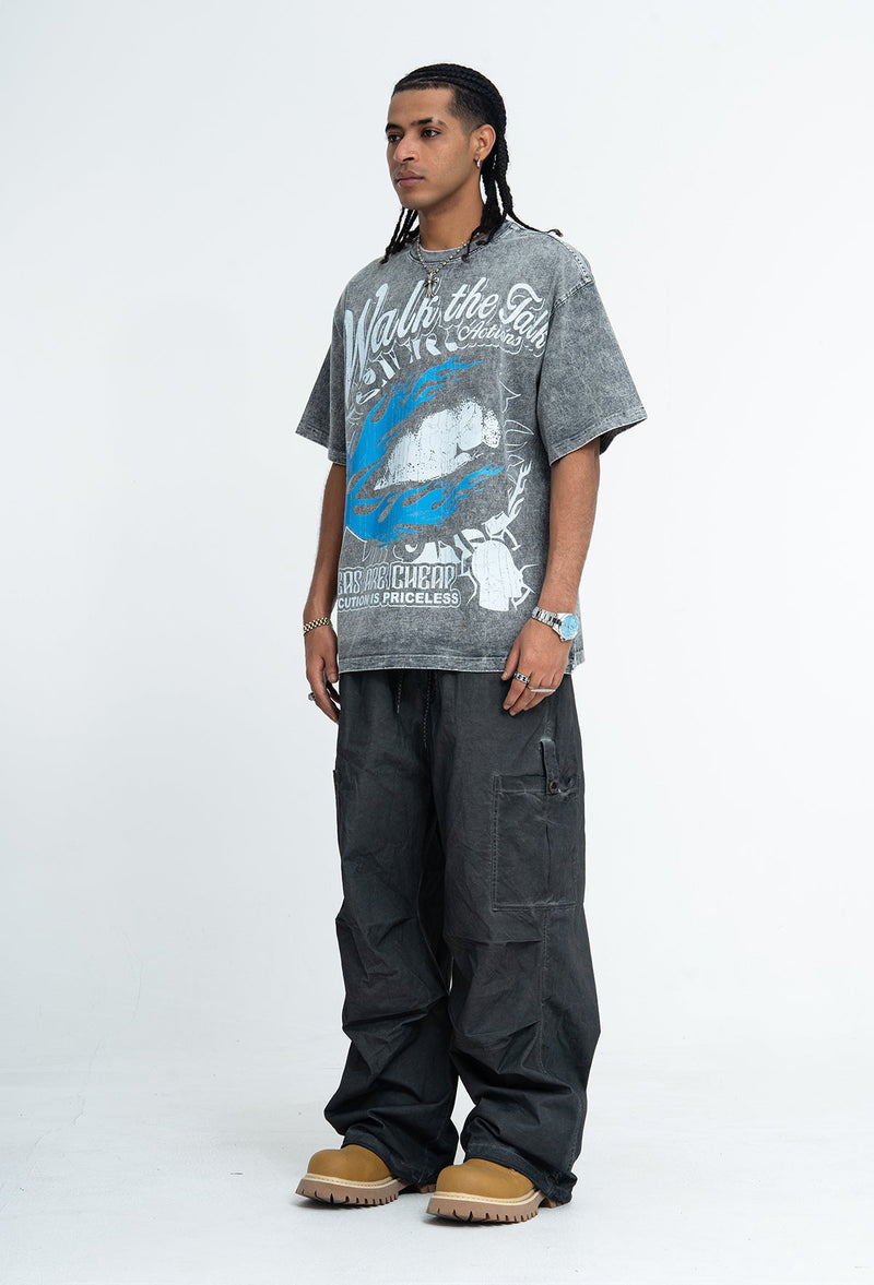 Model wearing a vintage washed gray graphic T-shirt with bold blue and white print, styled with loose black cargo pants