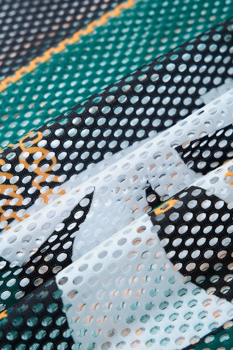 Close-up of Seakoff Royal Madness 84 mesh jersey fabric with layered black, white, teal, and orange perforated panels