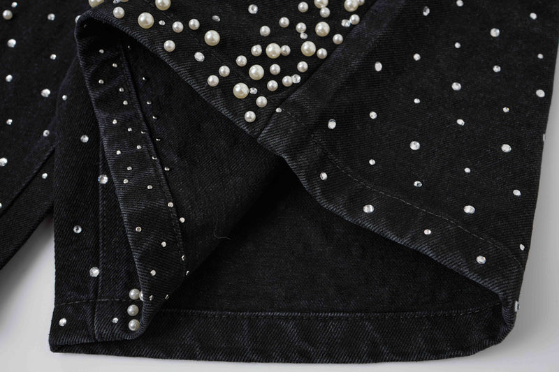 Close-up of black denim hem and side seam with pearl studs