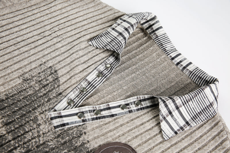 Close-up of beige sweater V-neck collar with plaid trim and snap buttons