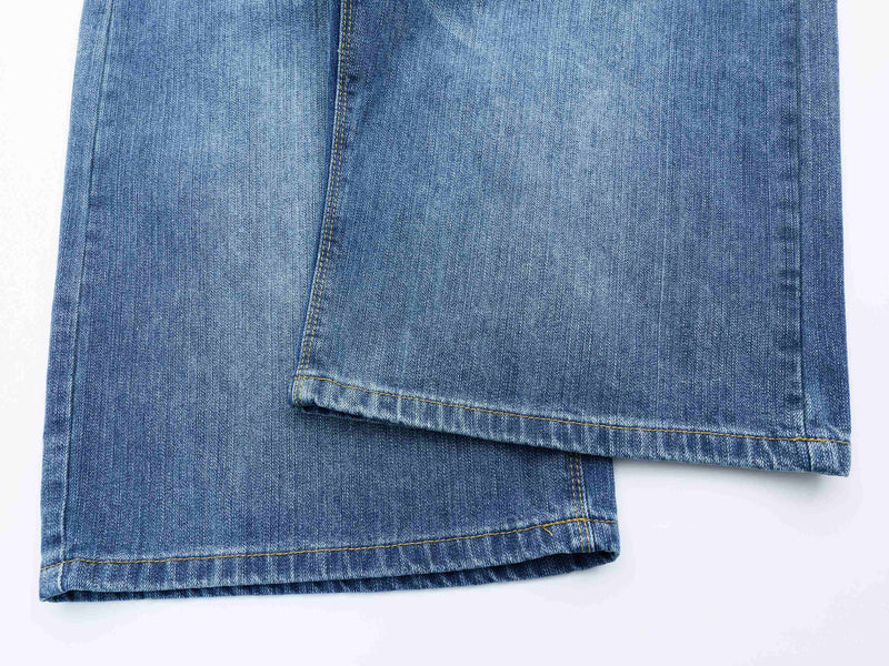 Close-up of the hem on blue denim shorts with wide-leg drape and topstitched edge