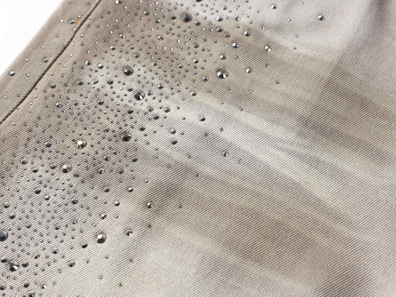 Close-up of rhinestones on the denim leg with light gray washed texture