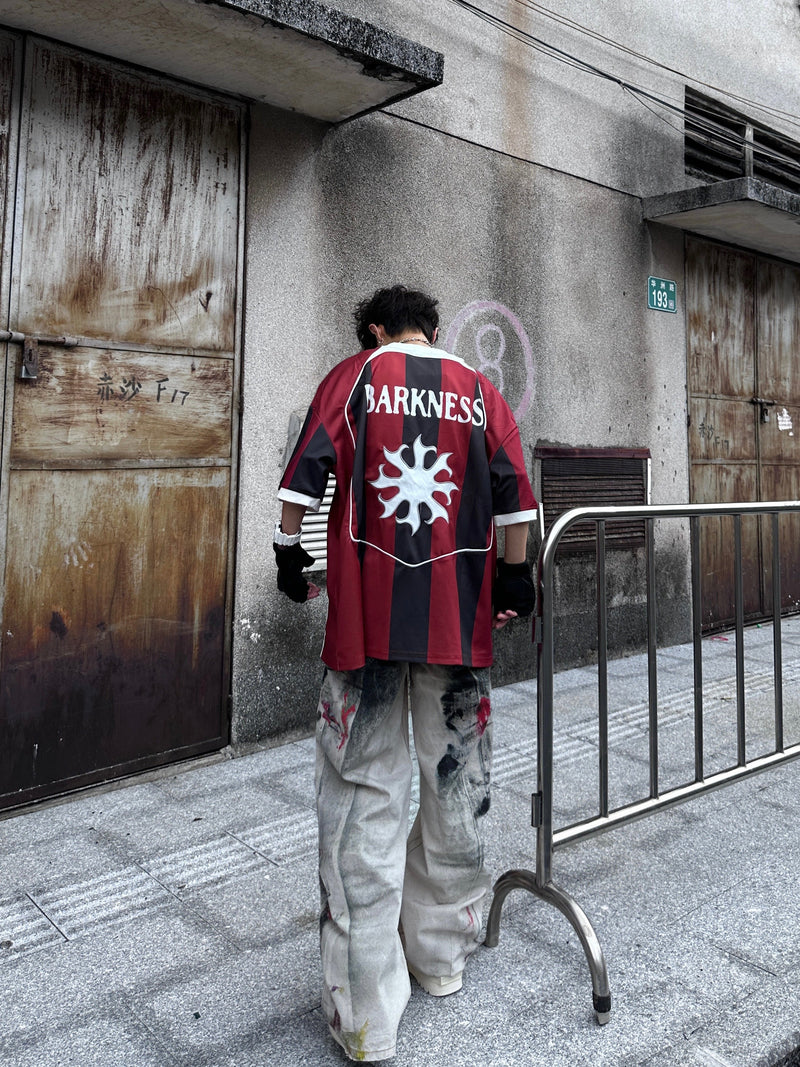 Oversized red and black vertical stripe soccer jersey tee with BARKNESS graphic on back and loose streetwear fit
