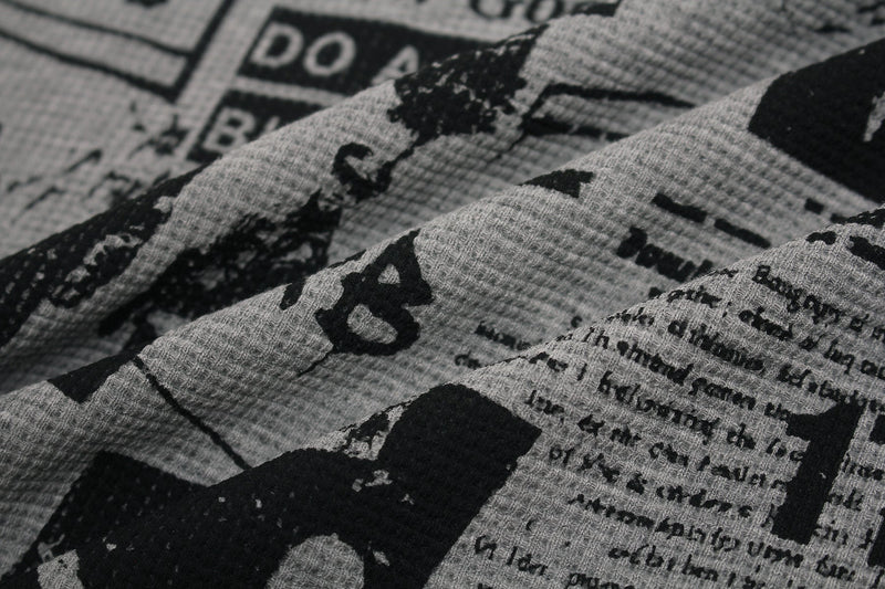 Close-up of gray graphic tee fabric with bold black collage-style gothic print and distressed text details