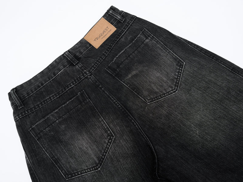 Back pocket close-up on black wide-leg denim with tan brand patch at waist