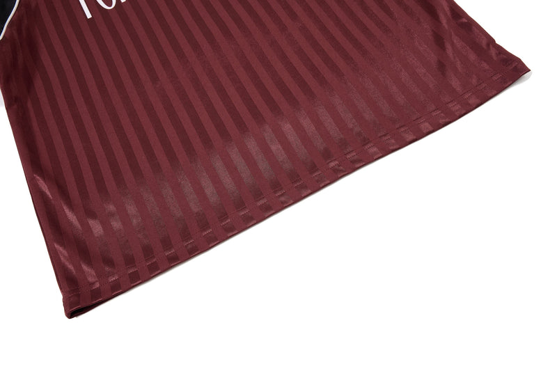 Maroon striped football jersey tee hem with subtle sheen and clean stitched edge on white background