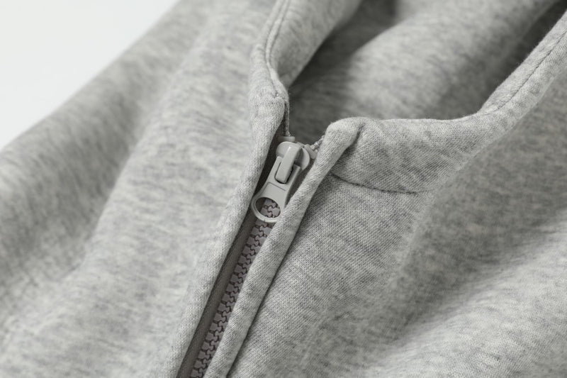 Close-up of grey zip hoodie collar and zipper pull at the neck
