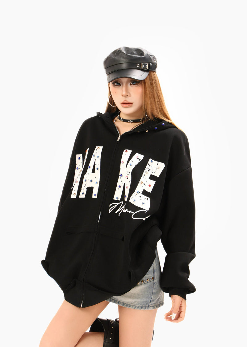 Black oversized zip hoodie worn by model with MAKE graphic and leather cap