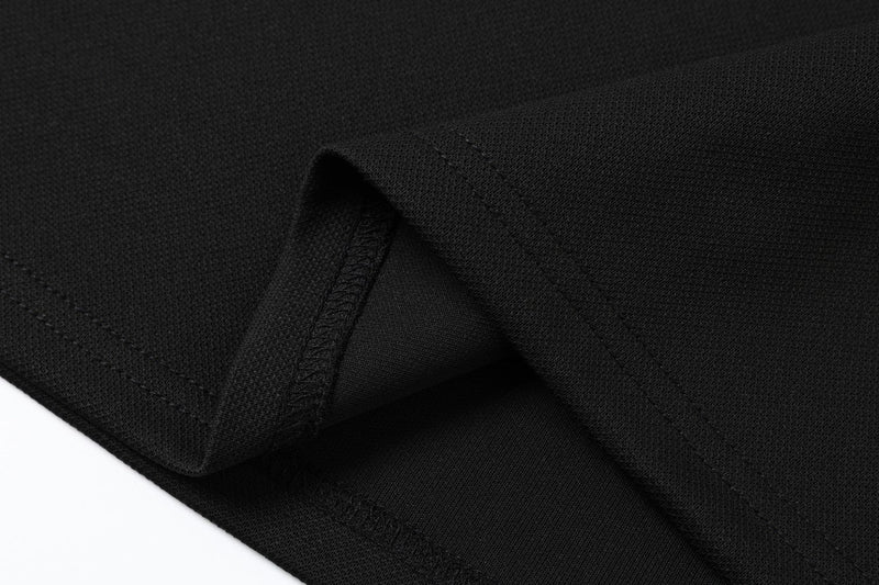 Close-up of black polo shirt fabric with folded sleeve and visible stitched hem details
