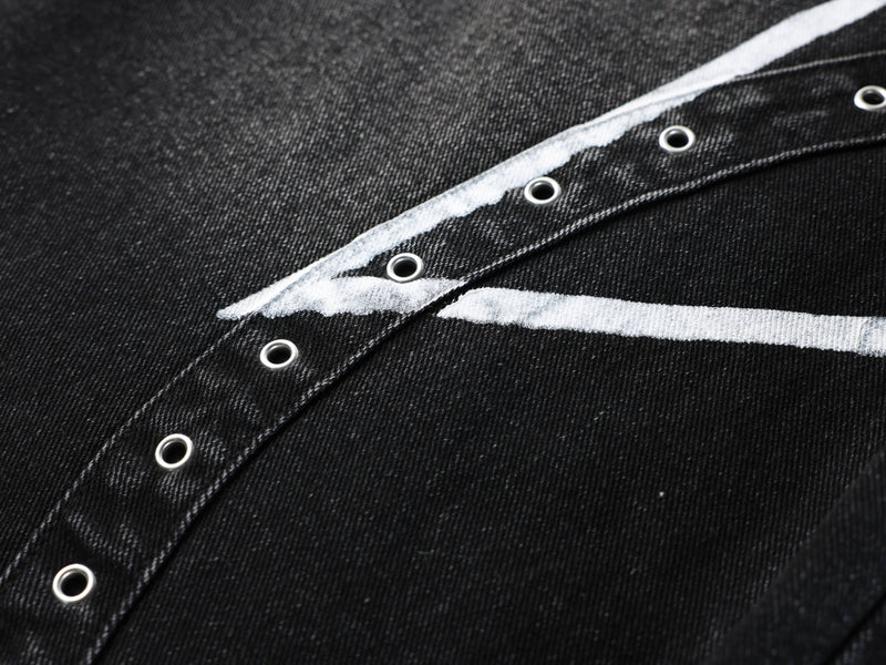 Close-up of black denim side panel with white printed stripe and metal grommets