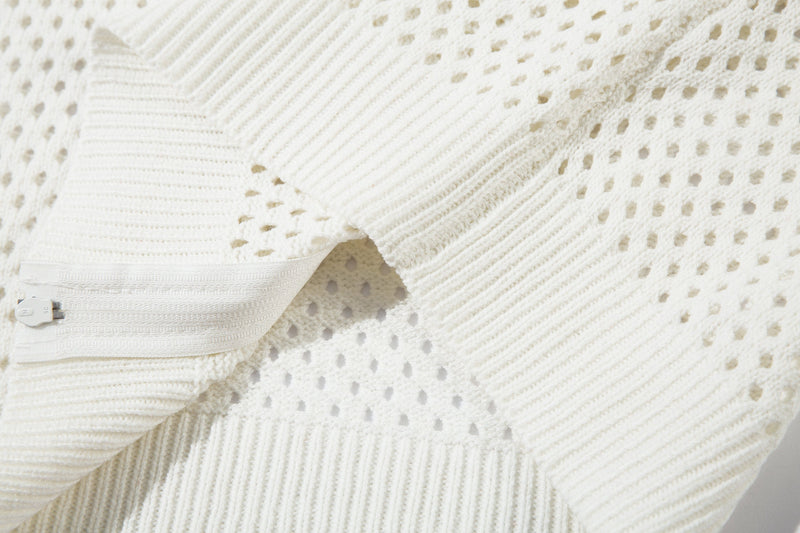 Close-up of white open-knit fabric and ribbed hem with zipper edge