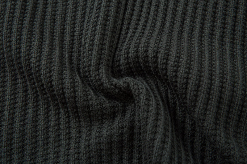 Close-up of dark ribbed knit sweater fabric folds and vertical ribbed texture