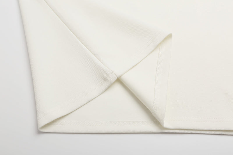 Close-up of folded cream polo shirt fabric with clean stitched hem and textured cotton finish