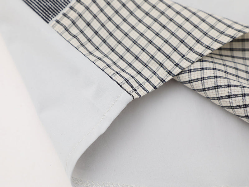 Close-up of a white plaid button-up shirt with navy checks and crisp cuff detailing, streetwear style fabric texture