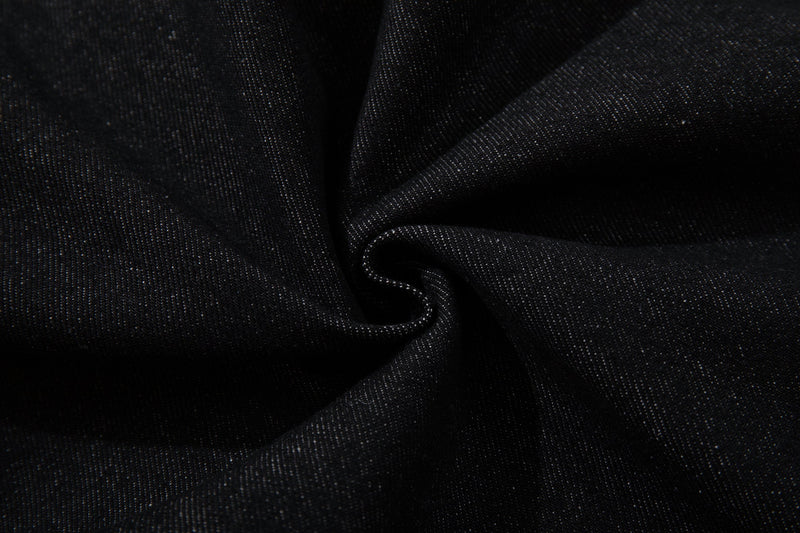 Close-up of black denim fabric texture with visible diagonal weave and soft folds