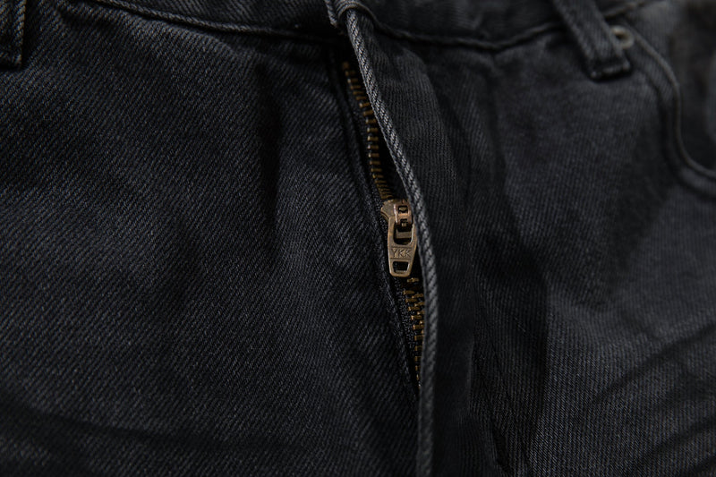 Close-up of front zipper fly on dark denim jeans with YKK zipper pull