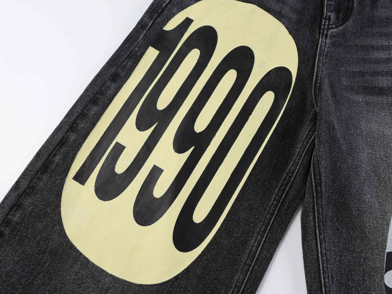 Close-up of black denim leg with large yellow graphic print