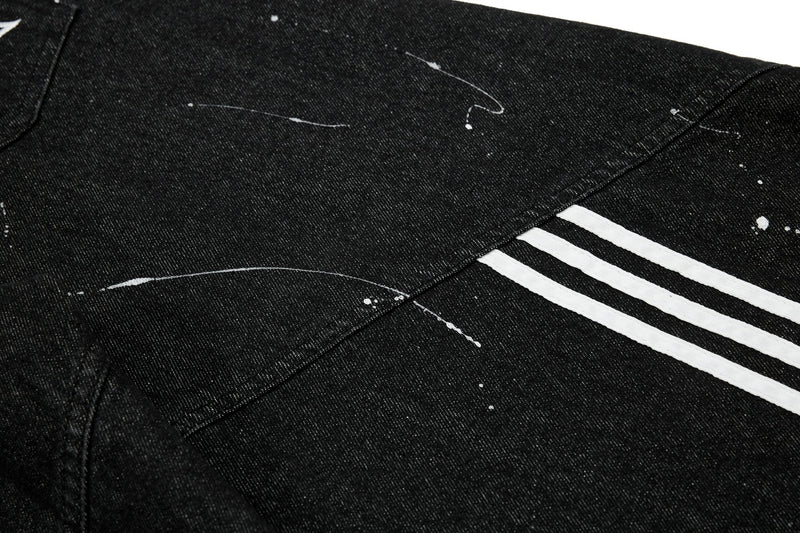 Black jeans leg with white triple side stripes and paint splatter, close-up