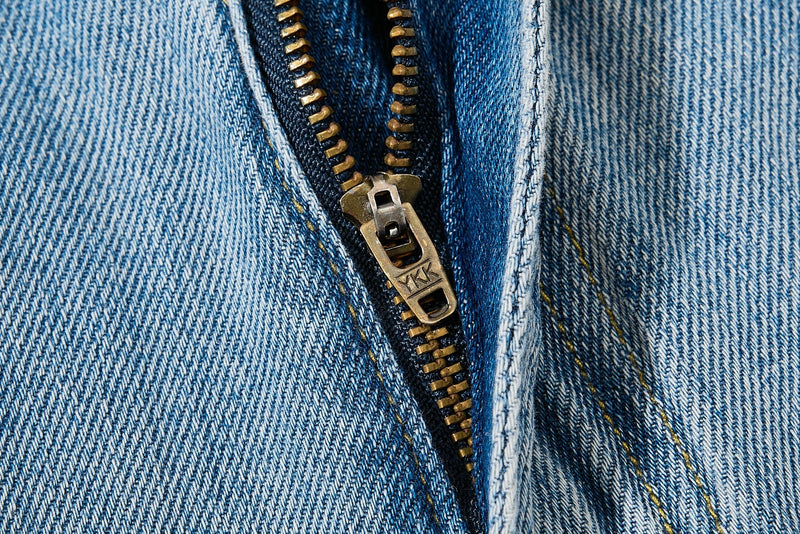 Close-up of denim fly zipper with brass teeth and metal pull tab