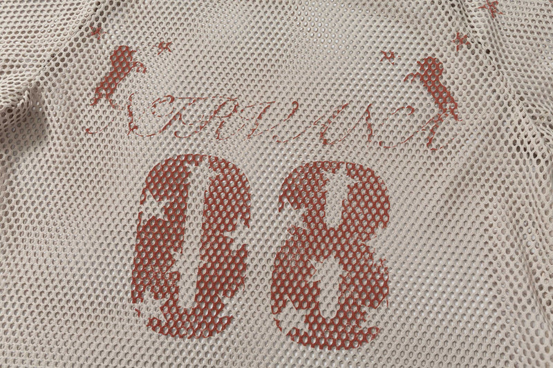 Close-up of a cream mesh football jersey tee with faded red retro lettering and oversized streetwear styling