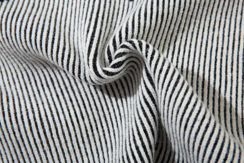 Close-up of striped ribbed knit sleeves gathered in a fold