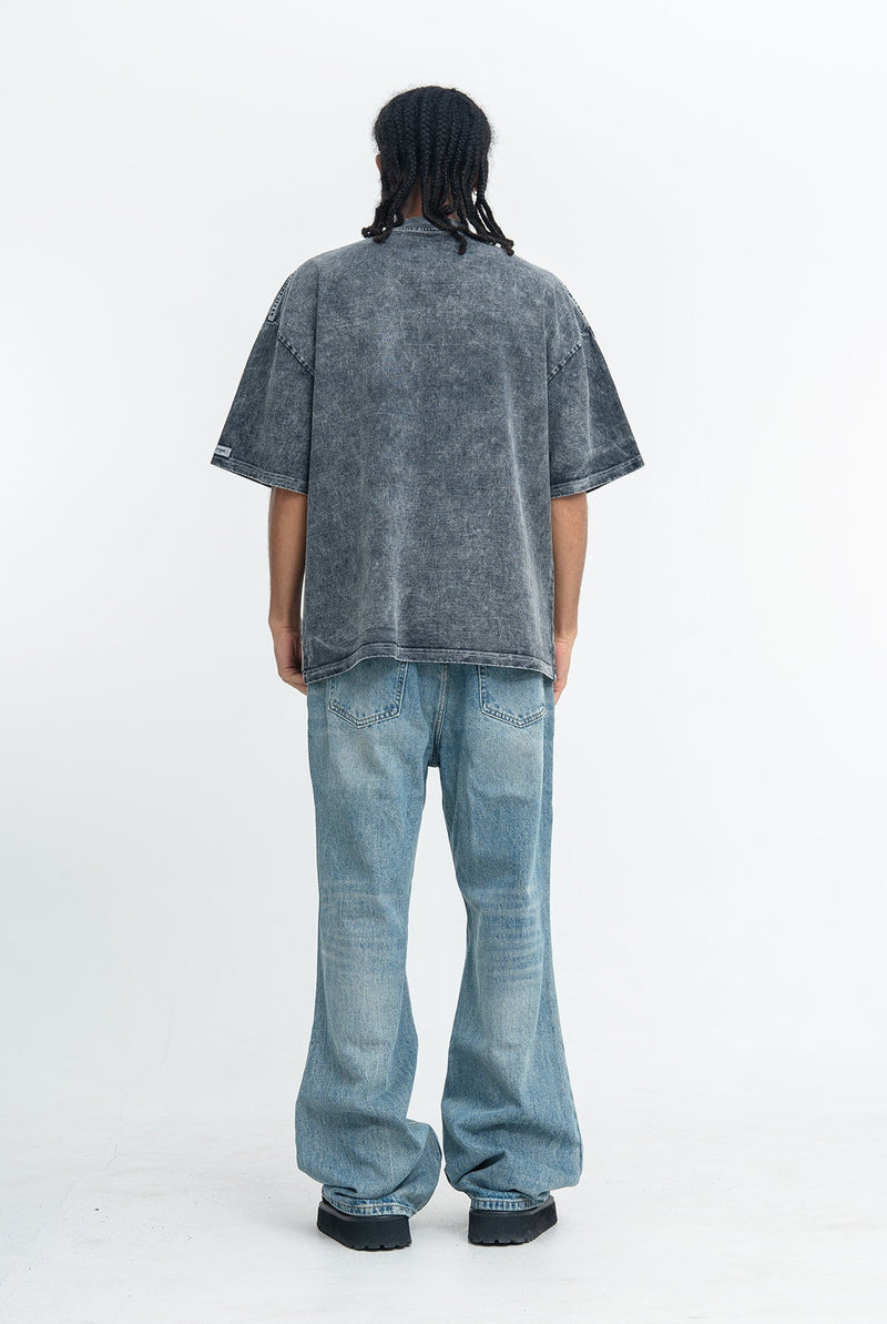 Oversized washed black graphic tee styled with light blue baggy jeans and chunky black sneakers, rear view