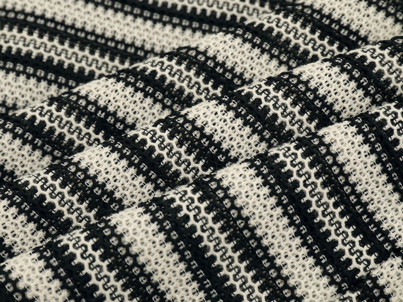 Close-up of black and cream striped knit fabric with open weave texture