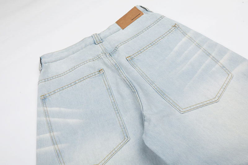 Back waist close-up of light wash jeans with leather patch and rear pocket