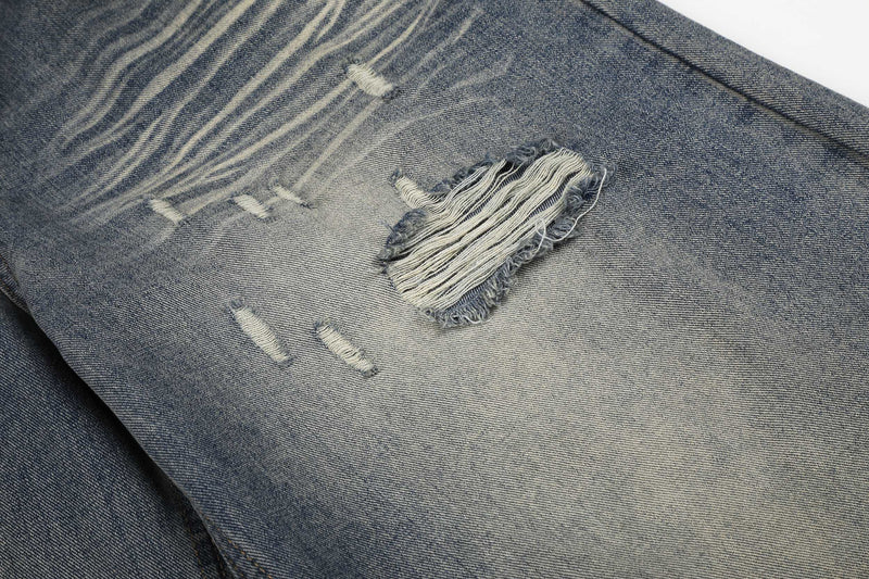 Close-up of distressed rip details on faded blue denim jeans