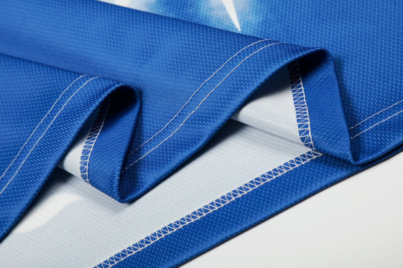 Close-up of blue mesh football jersey fabric with white stitching and layered hem detail
