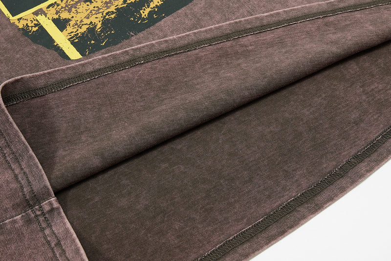 Close-up of a washed brown raglan tee with visible stitching and vintage graphic detail on the chest