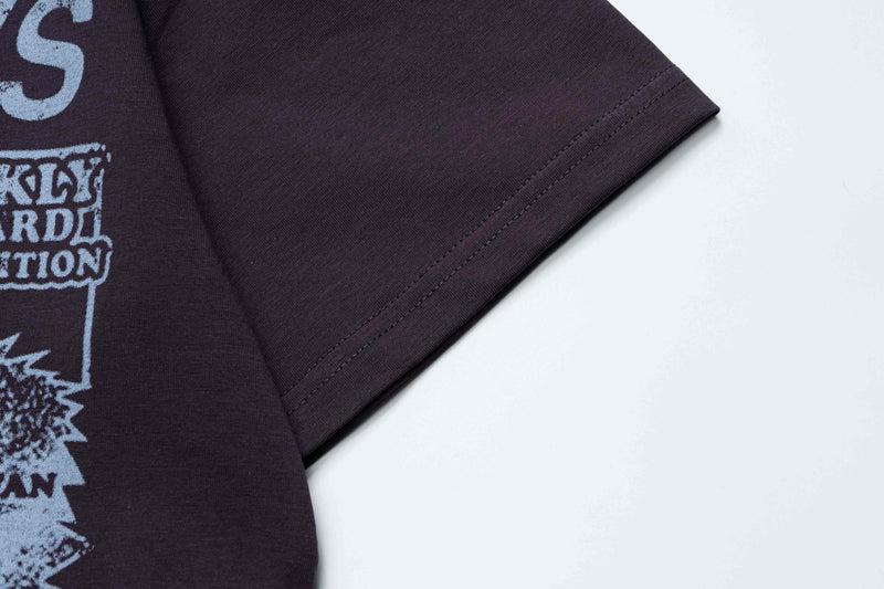 Dark oversized graphic tee with light blue newspaper-style print and stitched sleeve detail on a white background