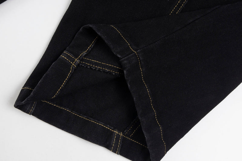 Close-up of a hemmed wide-leg jean cuff with tan stitching on black denim