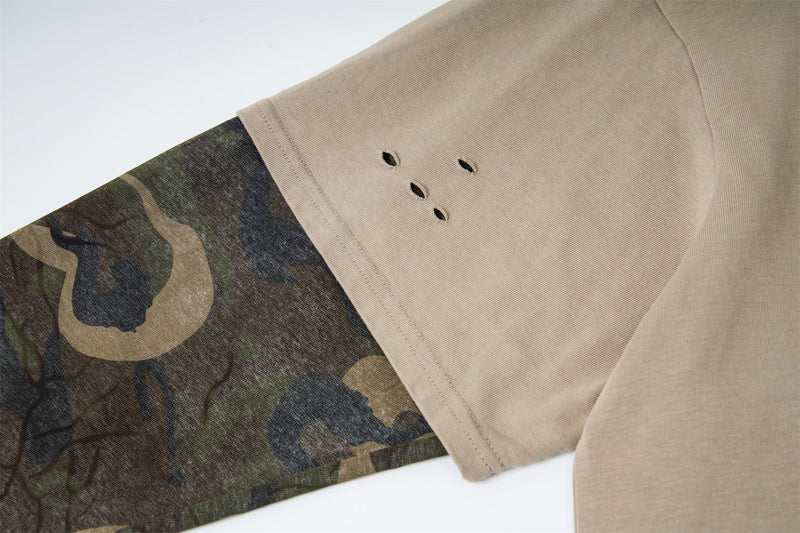 Close-up of beige sleeve with small distressed holes and camouflage underlayer
