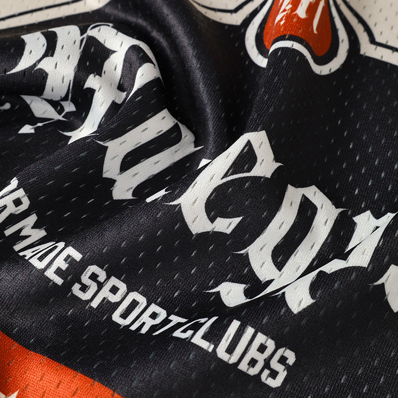 Close-up of a black collegiate football jersey with bold white lettering and orange accents, featuring a streetwear-inspired design