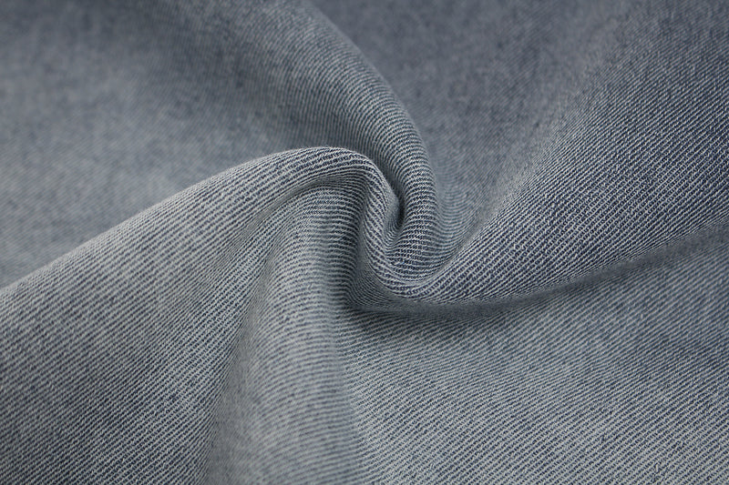 Close-up of faded blue distressed denim-style fabric with soft folded texture for a vintage washed T-shirt look