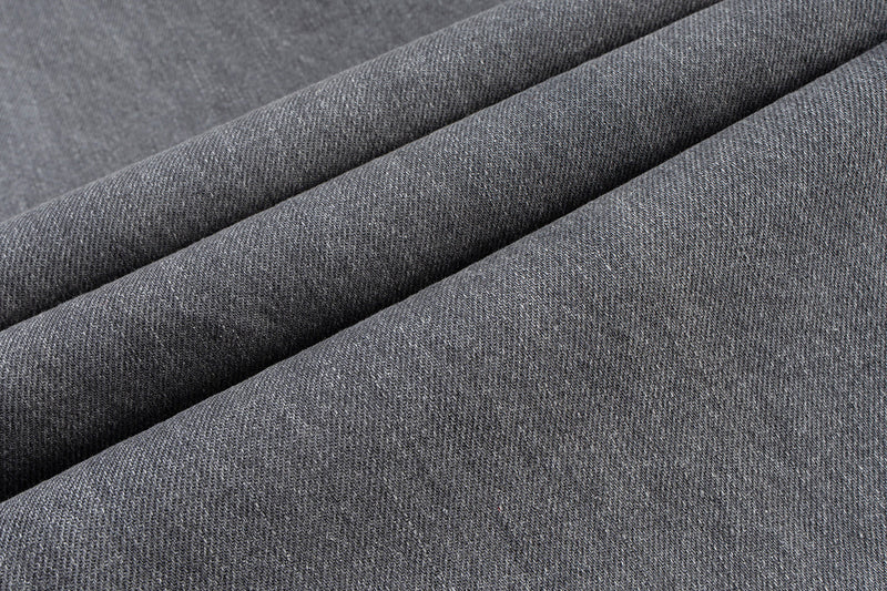 Close-up of grey denim fabric with visible diagonal twill texture and soft drape