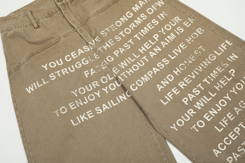 Front view of khaki pants with diagonal white slogan print across both legs